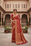 Indian woman wearing a red and gold Banarasi silk saree in a haveli courtyard